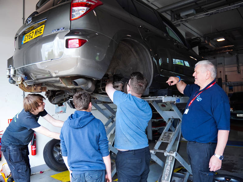Automotive students inspect a car in the automotive workshop at Highbury Campus